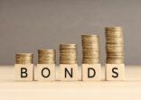 Bonds word in wooden blocks with coins stacked in increasing stacks