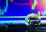 Arrangement of World globe crystal glass at office table on charts stock data on computer screen background. Global business on financial concept. World wide technology.