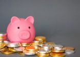 A savings or banking concept with a children’s Piggy bank surrounded by gold and silver coins with copy space