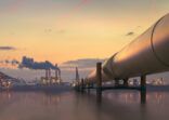 Oil pipeline in industrial district with factories at dusk